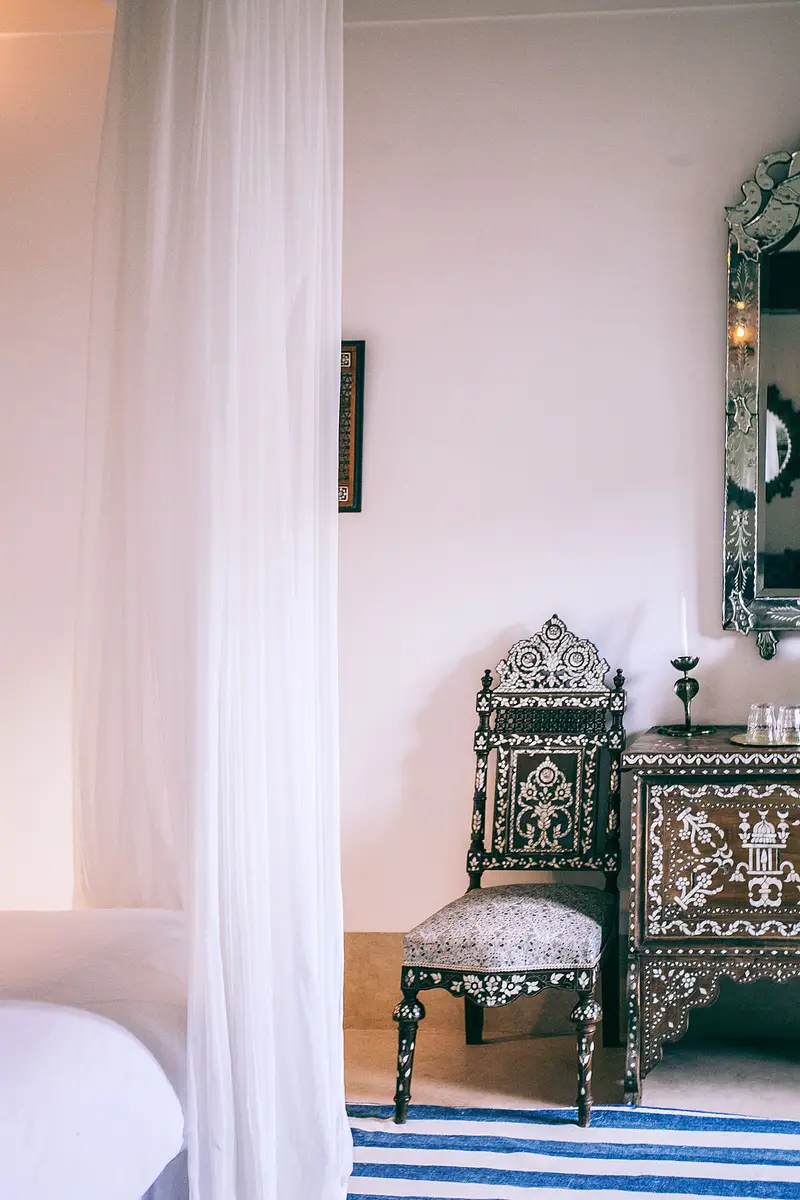 Chambre blanche aux voilages légers et mobilier marocain peint