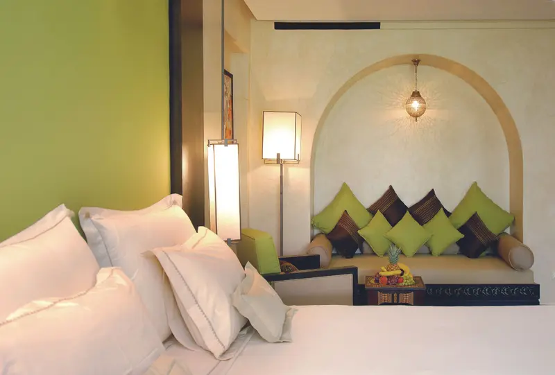 Chambre aux coussins vert menthe, lit blanc et niche voûtée