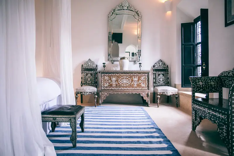 Chambre lumineuse avec tapis rayé, coiffeuse et miroir ciselé