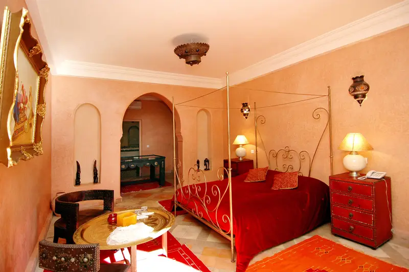 Suite avec lit à baldaquin en fer forgé, salon et tapis rouges